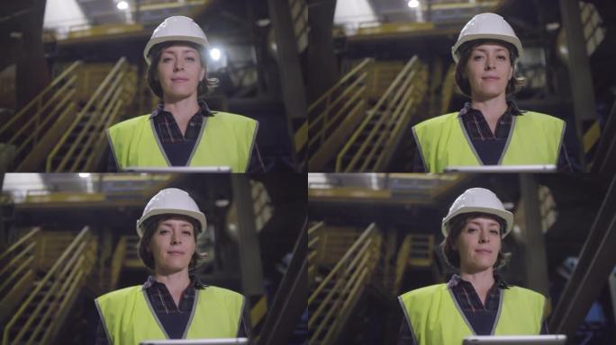 在制造工厂摆姿势的安全帽女技术员