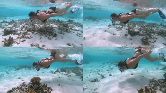 水下: 女性浮潜者沿着马尔代夫被毁的珊瑚礁潜水。