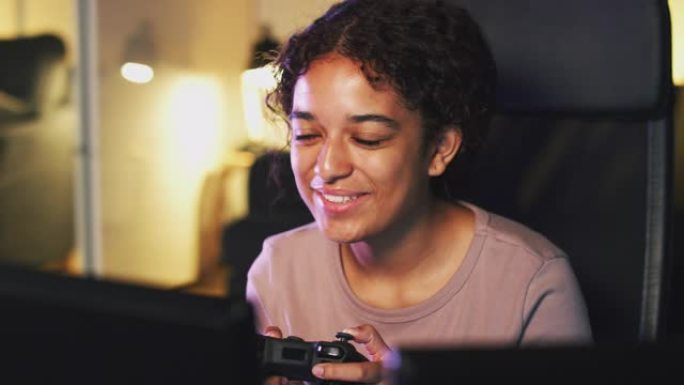 十几岁的女孩坐在家里屏幕前的椅子上，拿着电脑控制器和游戏
