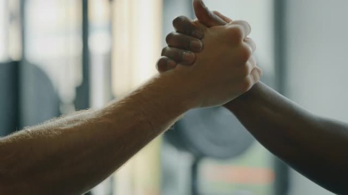 两名不同种族的专业年轻男性拳击手在健身房握手的电影慢动作镜头