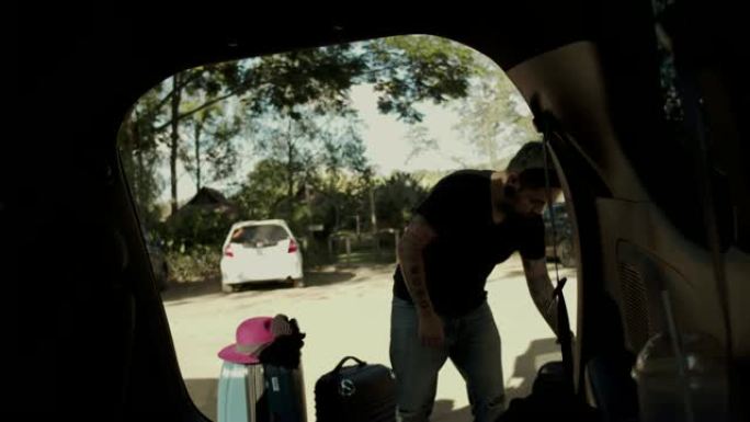 亚洲男子将行李装进汽车后备箱进行公路旅行。