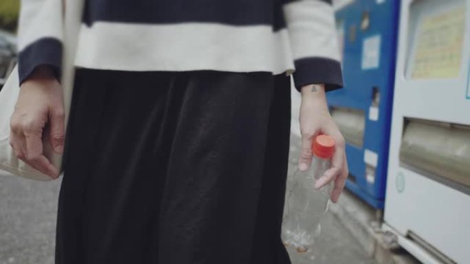 女人的手把空塑料瓶扔进垃圾桶
