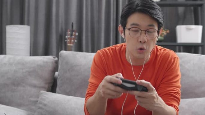 4k分辨率有吸引力的亚洲成年人拿着操纵杆或游戏控制器，在家玩视频游戏机。人的反应享受他在游戏中的胜利