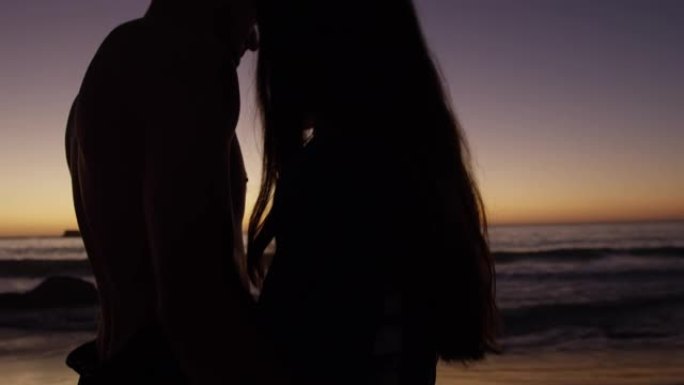 年轻的成年夫妇在日落时在海滩上放松