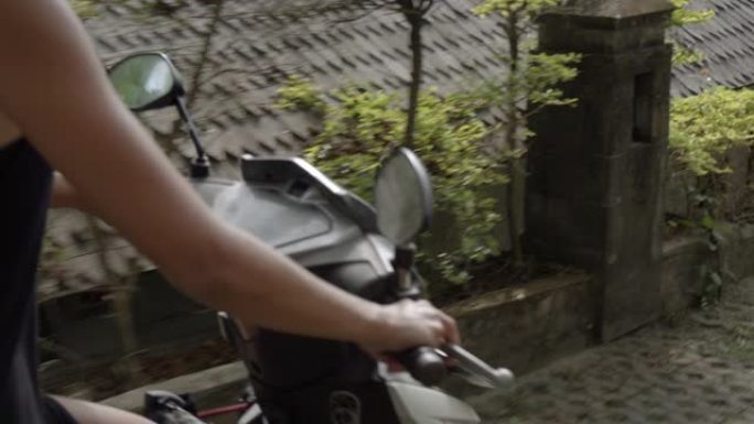 在热带小镇的街道上骑踏板车的女人