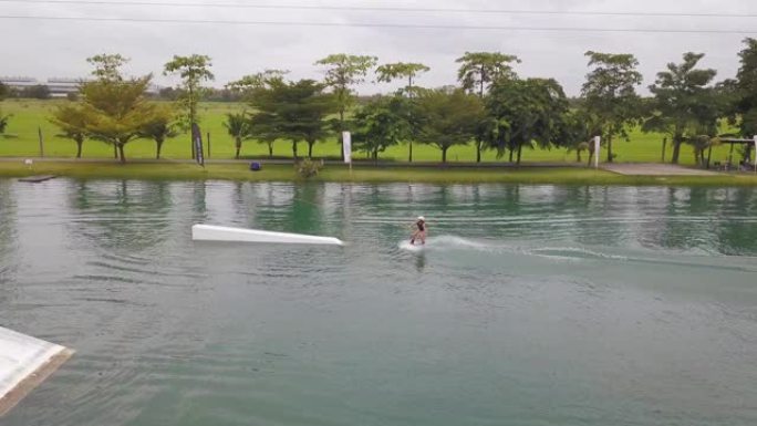 空中: 凉爽的滑水者在被钢缆滑水机拖拉时在河上急转弯