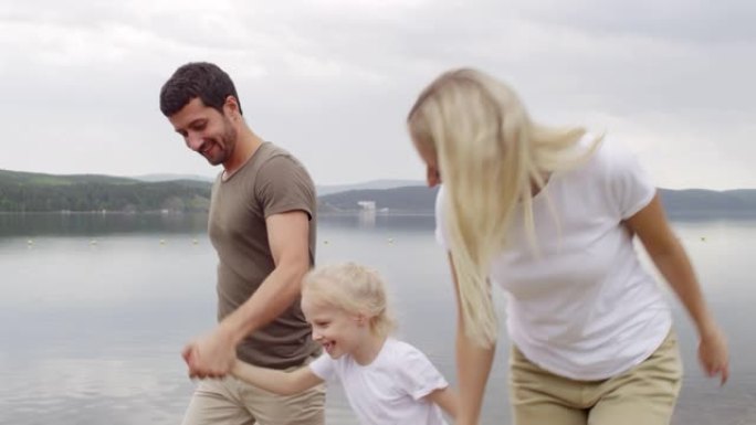 幸福的三口之家享受在湖边散步