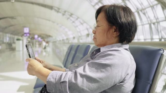 高级女乘客在出发航站楼机场触摸手机并使用笔记本电脑