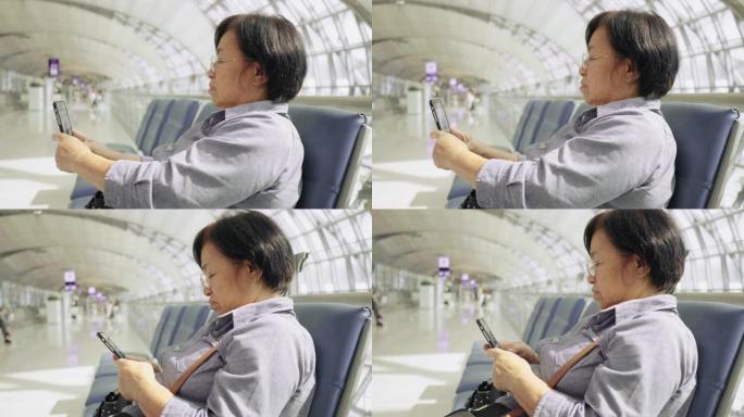 高级女乘客在出发航站楼机场触摸手机并使用笔记本电脑