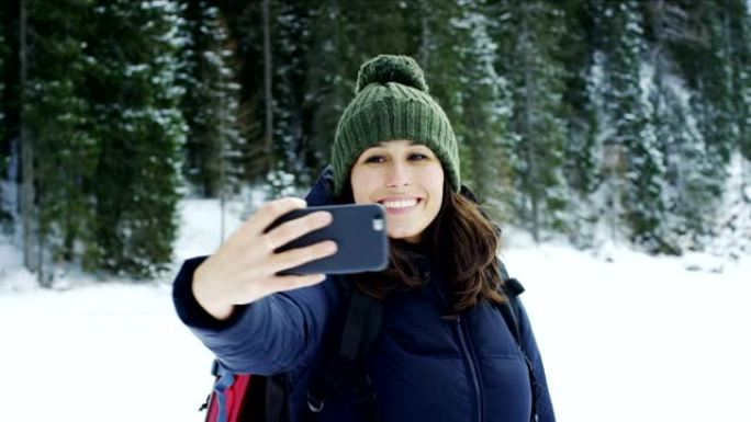 在度假的山区，一个女孩使用手机或智能手机发短信，打电话，拍照，自拍和视频通话在家中的朋友和家人