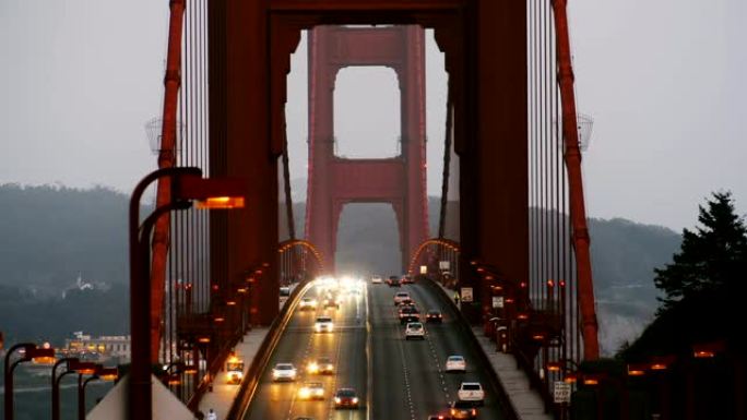 美国旧金山日落时分，晚间汽车交通灯沿着标志性的金门大桥移动的慢动作镜头。