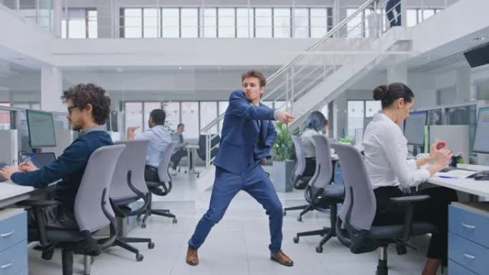 年轻开朗英俊的商务经理穿着西装，领带在办公室跳舞。在现代开放式办公室中，多元化且积极进取的商人在计算