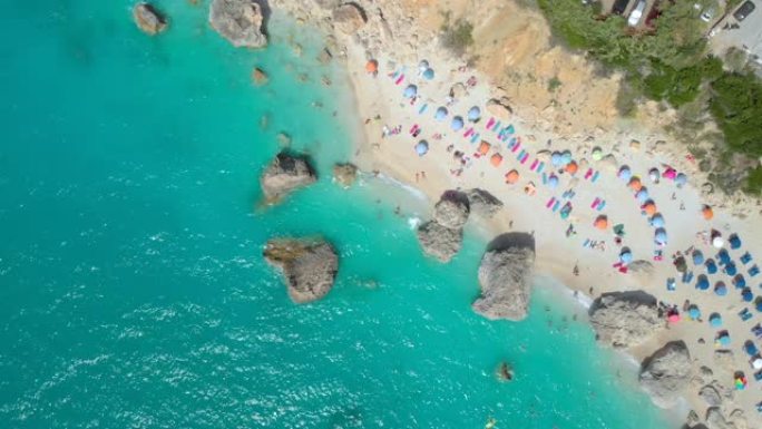 空中: 在莱夫卡达 (Lefkada) 的沙滩上放松的无忧无虑的游客上方飞行。