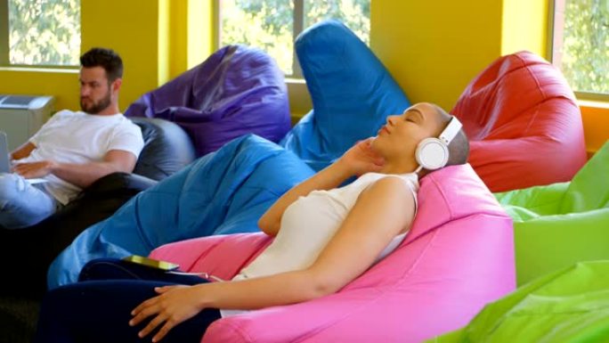 现代办公室4k中年轻高加索女性高管在手机上听音乐的侧视图