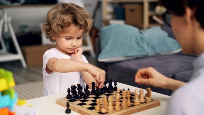聪明的男孩下棋与母亲移动的棋子表达积极的情感