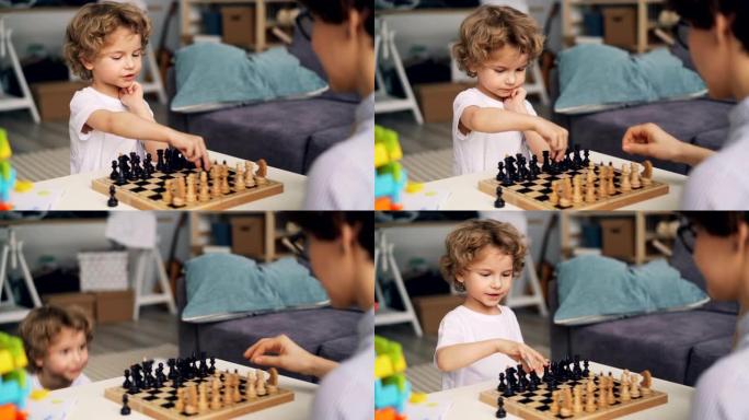 聪明的男孩下棋与母亲移动的棋子表达积极的情感