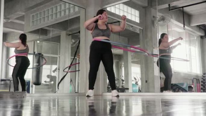 超重的女人在健身馆玩呼啦圈。