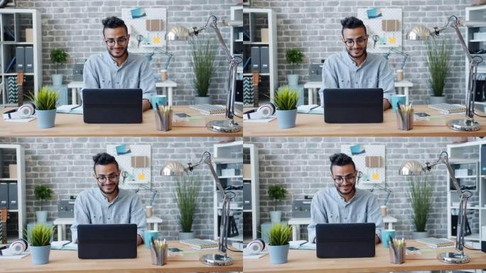 阿拉伯上班族在工作场所使用笔记本电脑微笑的慢动作