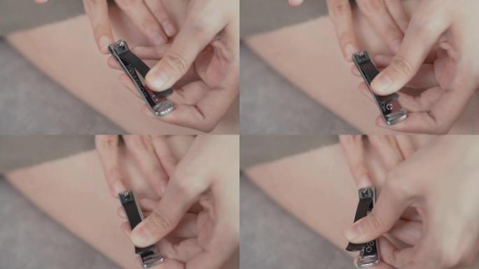 亚洲妇女在家用指甲刀在指甲上剪指甲