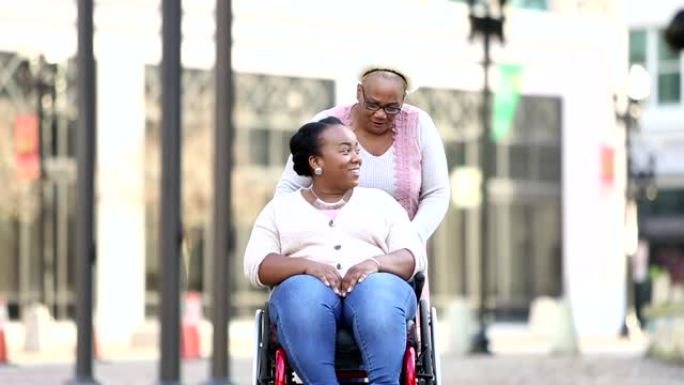 在城市街道上与资深母亲坐轮椅的女人