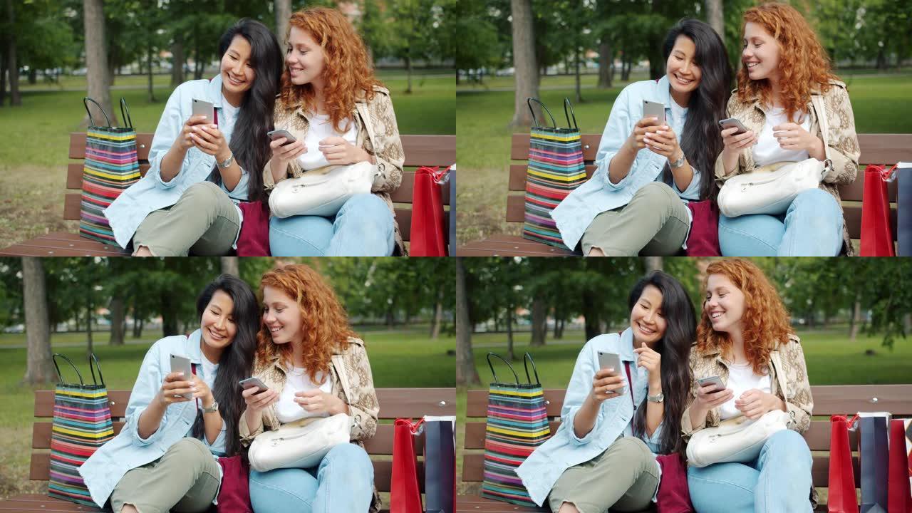 快乐的女孩一起在公园的长凳上使用智能手机聊天放松