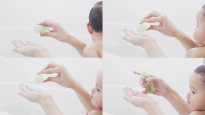 亚洲母亲手拿液体肥皂给她的女婴洗澡