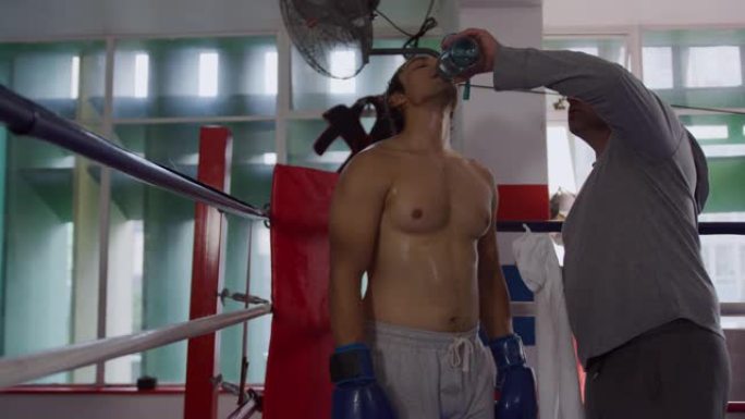 高加索教练在拳击场上给高加索运动员喝水