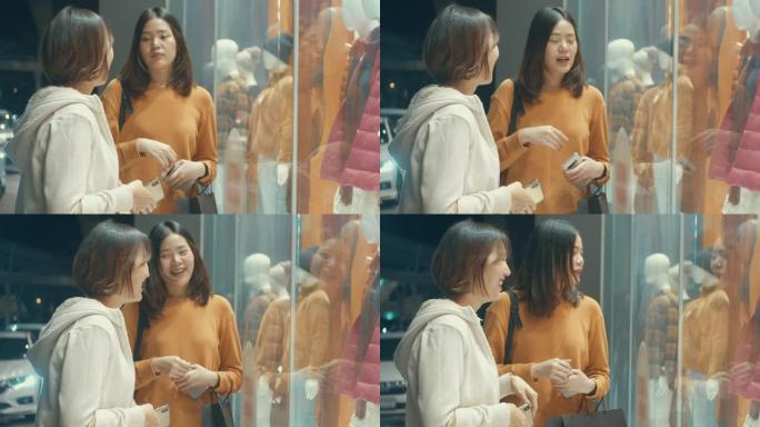 两名年轻的亚洲妇女看着商店的橱窗，慢动作
