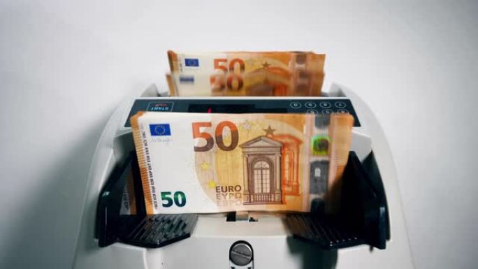 一个人将一捆欧元钞票放入计数机。