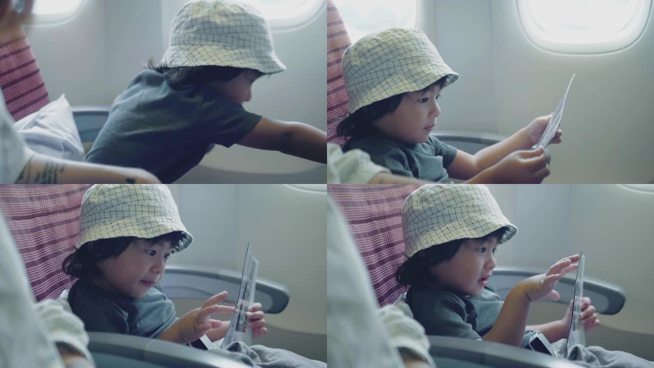 亚洲男婴飞机飞行阅读书。