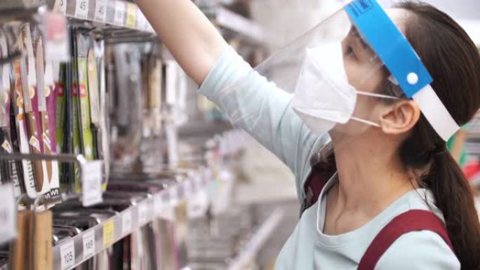 亚洲女人戴着口罩和面罩在超市购物，新型冠状病毒肺炎病毒后的新常态生活