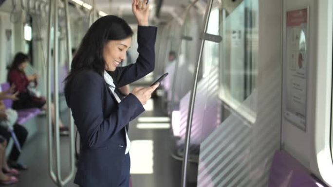 年轻的亚洲女商人在地铁地铁的公共交通中使用智能手机。女人上网