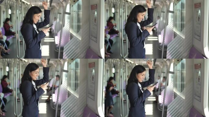 年轻的亚洲女商人在地铁地铁的公共交通中使用智能手机。女人上网