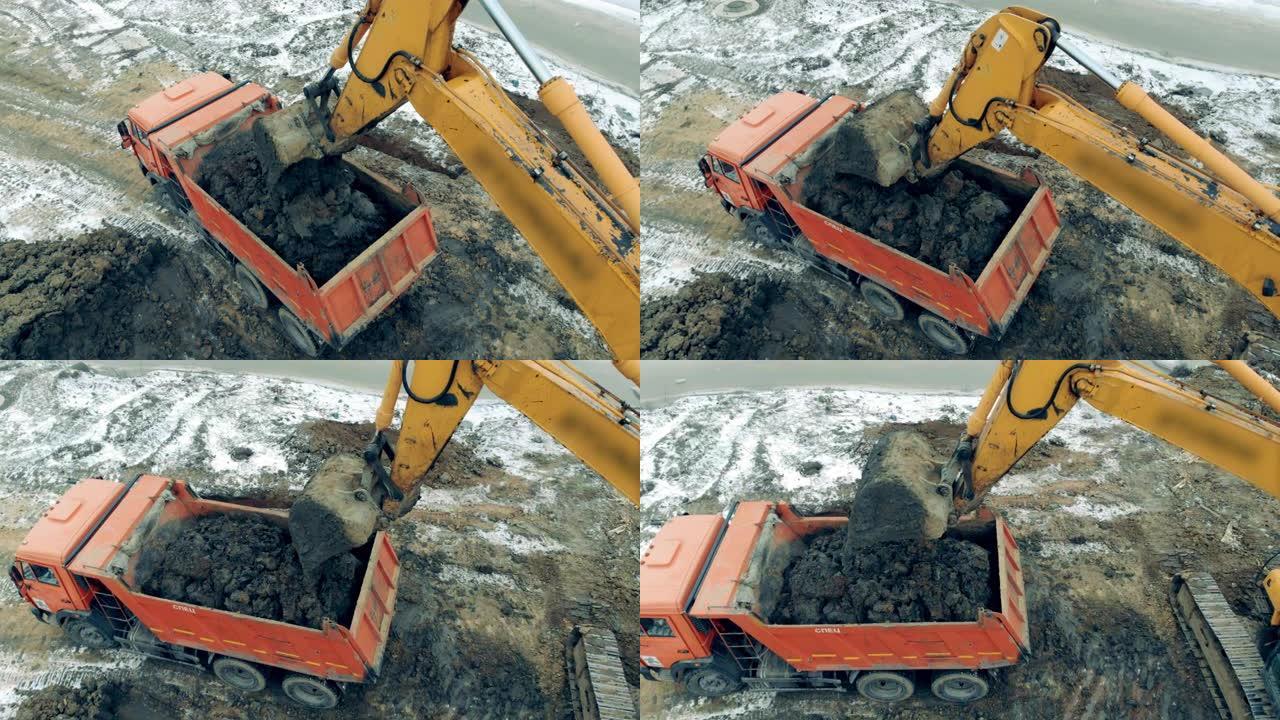 一辆建筑挖掘机用沙子和石头装载卡车。