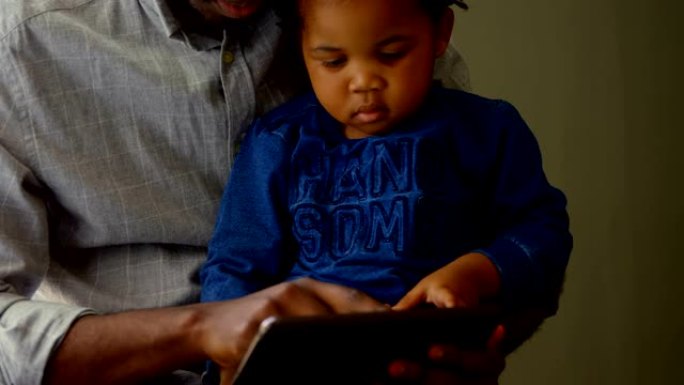 黑人父子在舒适的家庭4k中使用数字技术的前视图