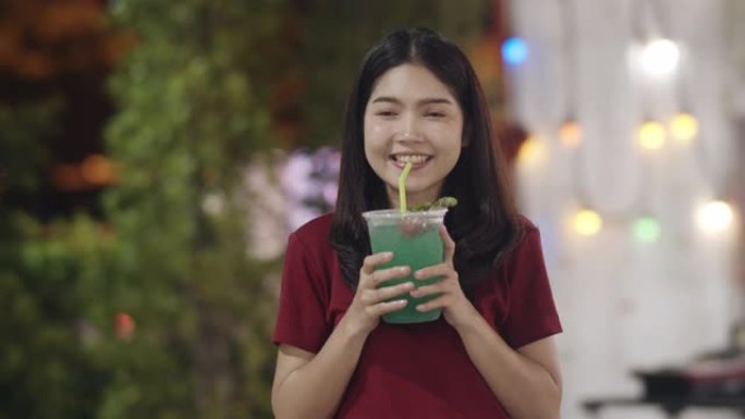 亚洲年轻女子在泰国曼谷旅行，美丽的女性在考山路喝鸡尾酒感到快乐。妇女旅游吃街头食品泰国概念。慢动作镜
