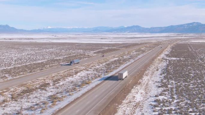 空中: 白色卡车将货物运送到风景秀丽的高速公路上，横穿雪白的沙漠