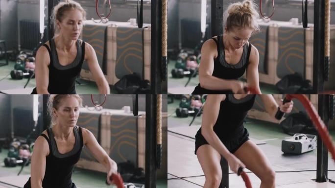 年轻美丽专注的运动金发女子用战斗绳锻炼，专注于大型健身房的训练。