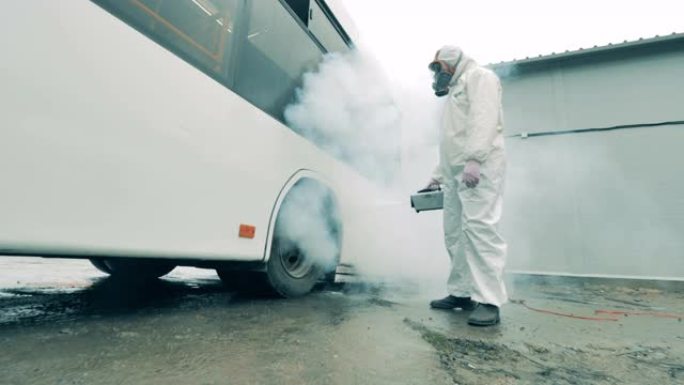 男子在冠状病毒大流行期间用喷雾器消毒公共汽车。消毒，消毒概念。