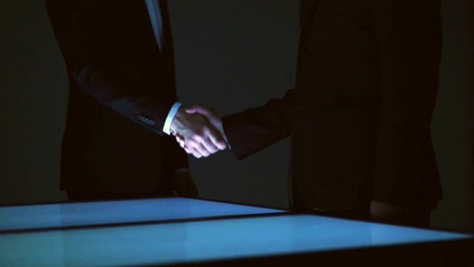 两个商人在屏幕上方握手。慢动作