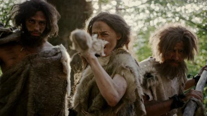 女性领袖和两名穿着动物皮的原始穴居人用石尖矛威胁敌人，尖叫，捍卫史前时代的洞穴和领土。尼安德特人/智