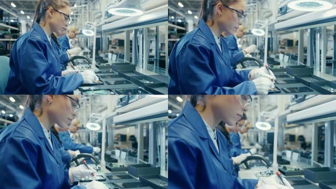 穿着蓝色工作服和防护眼镜的女电子工厂工人正在组装带有镊子和螺丝刀的智能手机。高科技工厂设施，后台有更