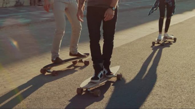 一群女孩和男孩在滑板上穿过时尚的潮人区。美丽的年轻人滑板穿过现代时尚的城市街道。移动慢动作相机拍摄聚