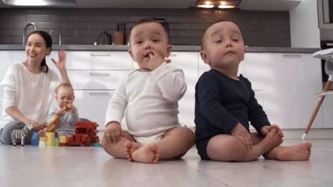 亚洲三胞胎和女人坐在厨房的地板上