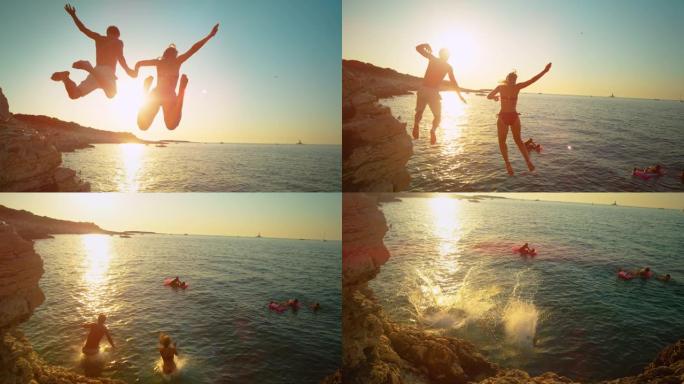 镜头耀斑: 无忧无虑的游客在日落时跳海时手牵手。