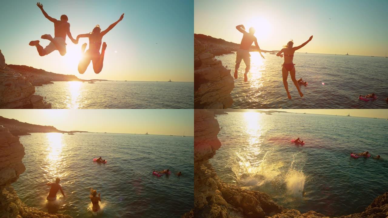 镜头耀斑: 无忧无虑的游客在日落时跳海时手牵手。