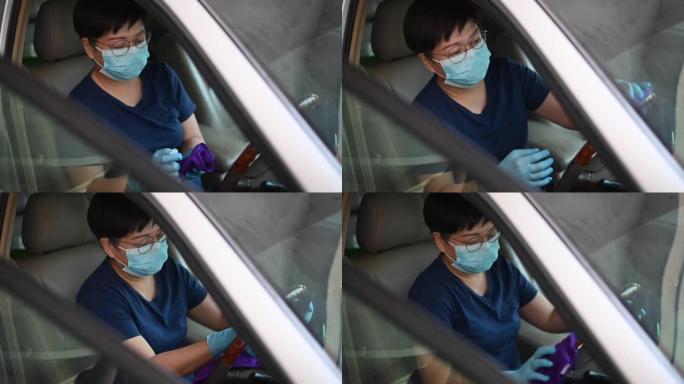 一名亚洲华人女性戴口罩和手套在限制行动期间外出购物前对汽车内部进行消毒和清洁
