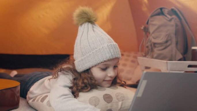 野营旅行中使用笔记本电脑的小女孩