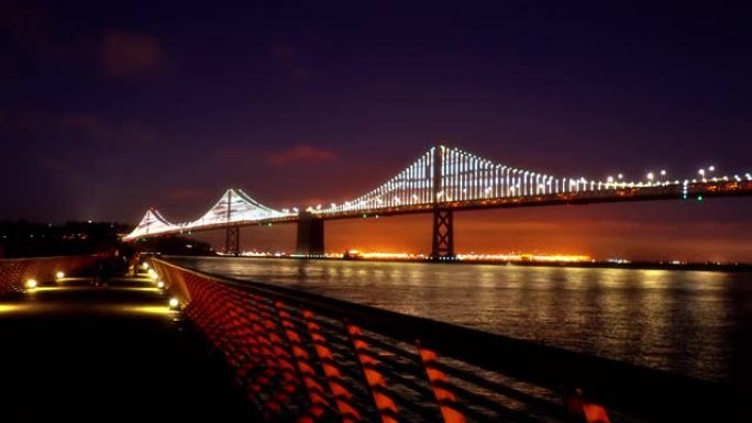 晚上旧金山的照明桥。行人的彩色路径。天际线。河。