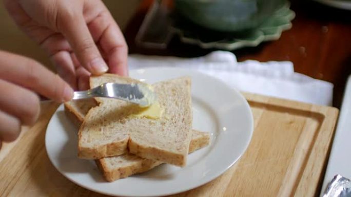 将黄油撒在一片面包上作为早餐